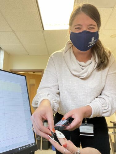 A student applying a test to a person's hand. 