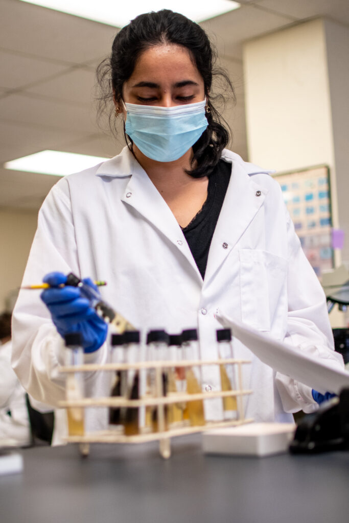 A student examines a test tube in lab. 