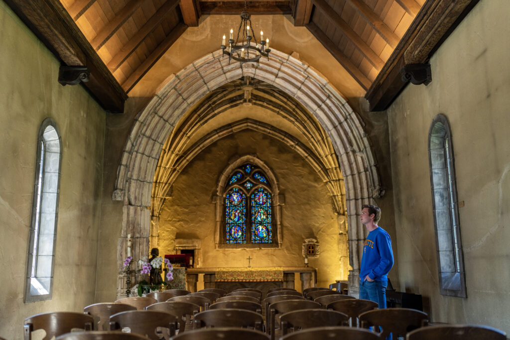 Noah Smith looking and standing inside of St. Joan of Arc Chapel.