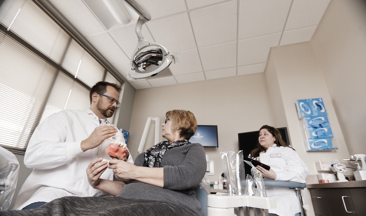 Dr. Arndt Guentsch speaks with a patient in a dental chair.