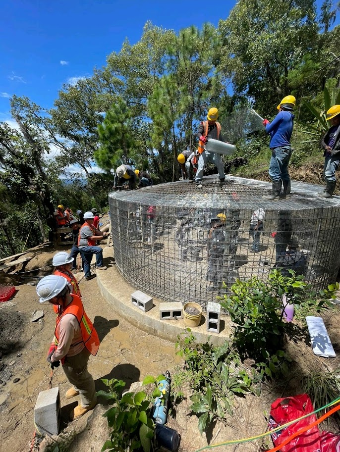 students and community members work on a large, partially built tank.