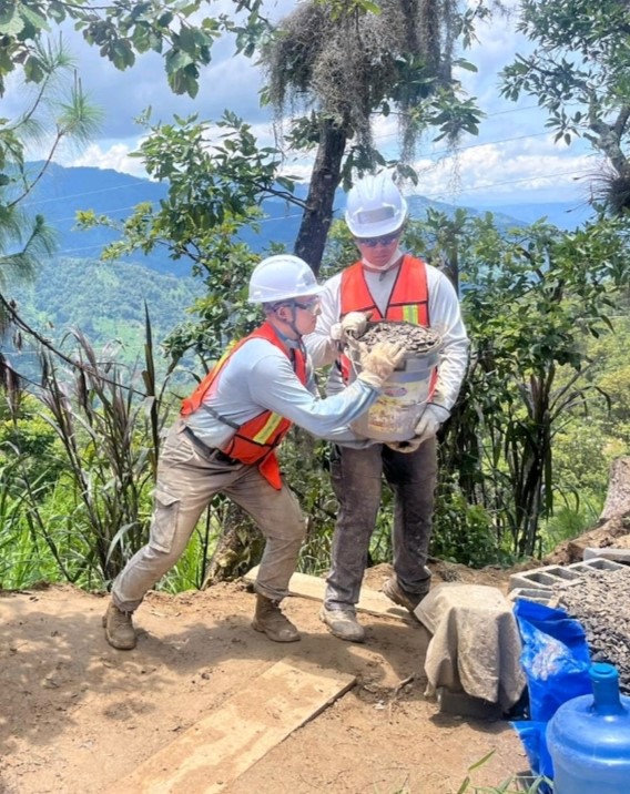 students transfer building materials via a bucket with a jungle backdrop.