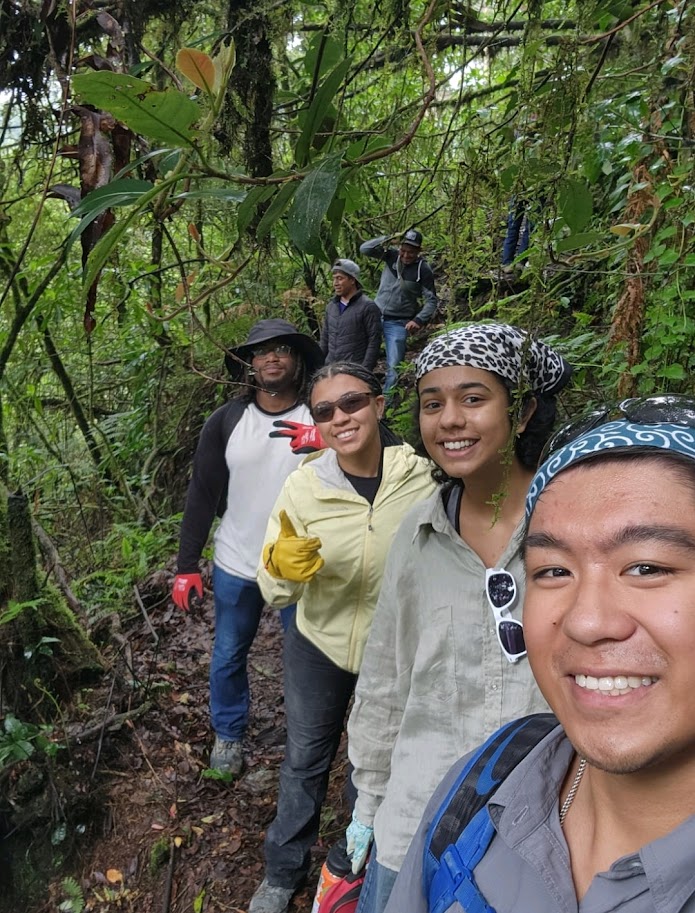 students pose in a selfie while walking through a jungle path.