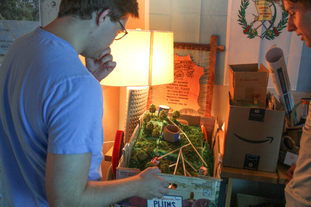 A student looks over a scale model of a previous project implementation.