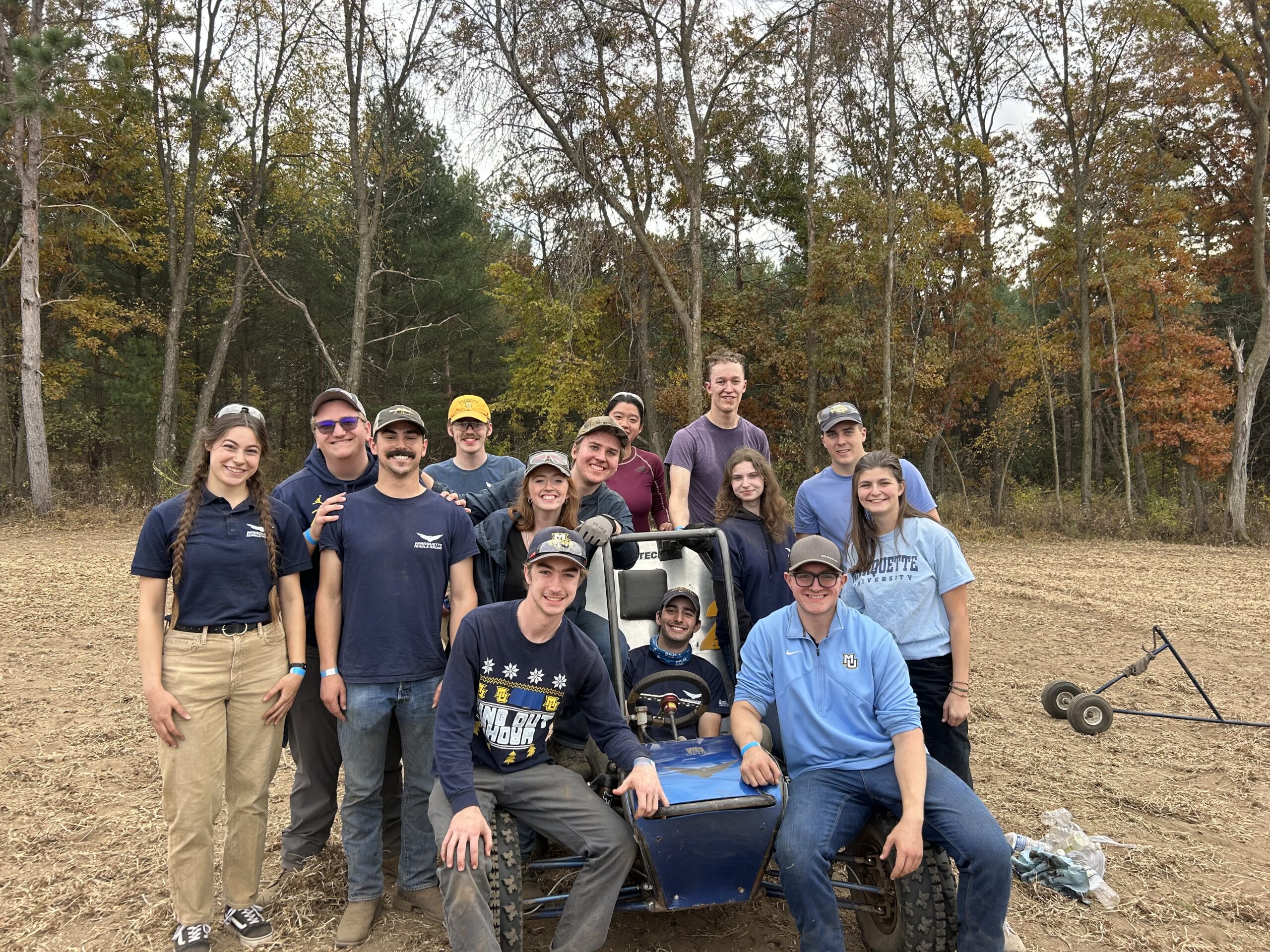 14 students posing with stationary off-road vehicle