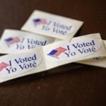 Stickers with an American flag that say "I voted" in English and Spanish.