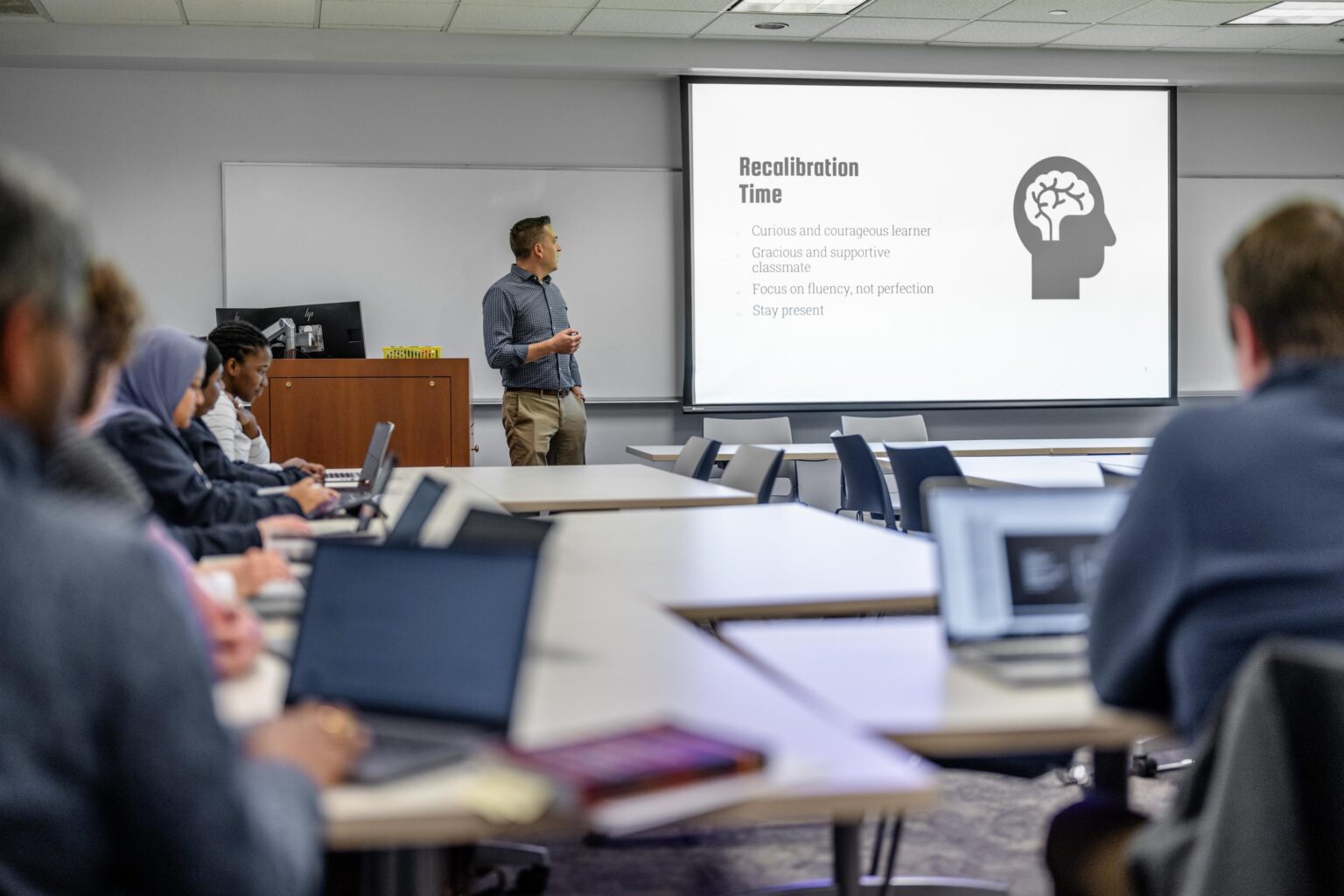 A professor teaches at the front of a classroom.