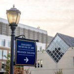 A blue sign pointing to the Haggerty Museum of Art with the museum in the background.