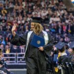 A Marquette student waves at the crowd after receiving their diploma during the 2024 Commencement ceremony.