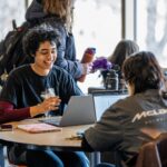 Students sit together at a table on Marquette's Raynor bridge.