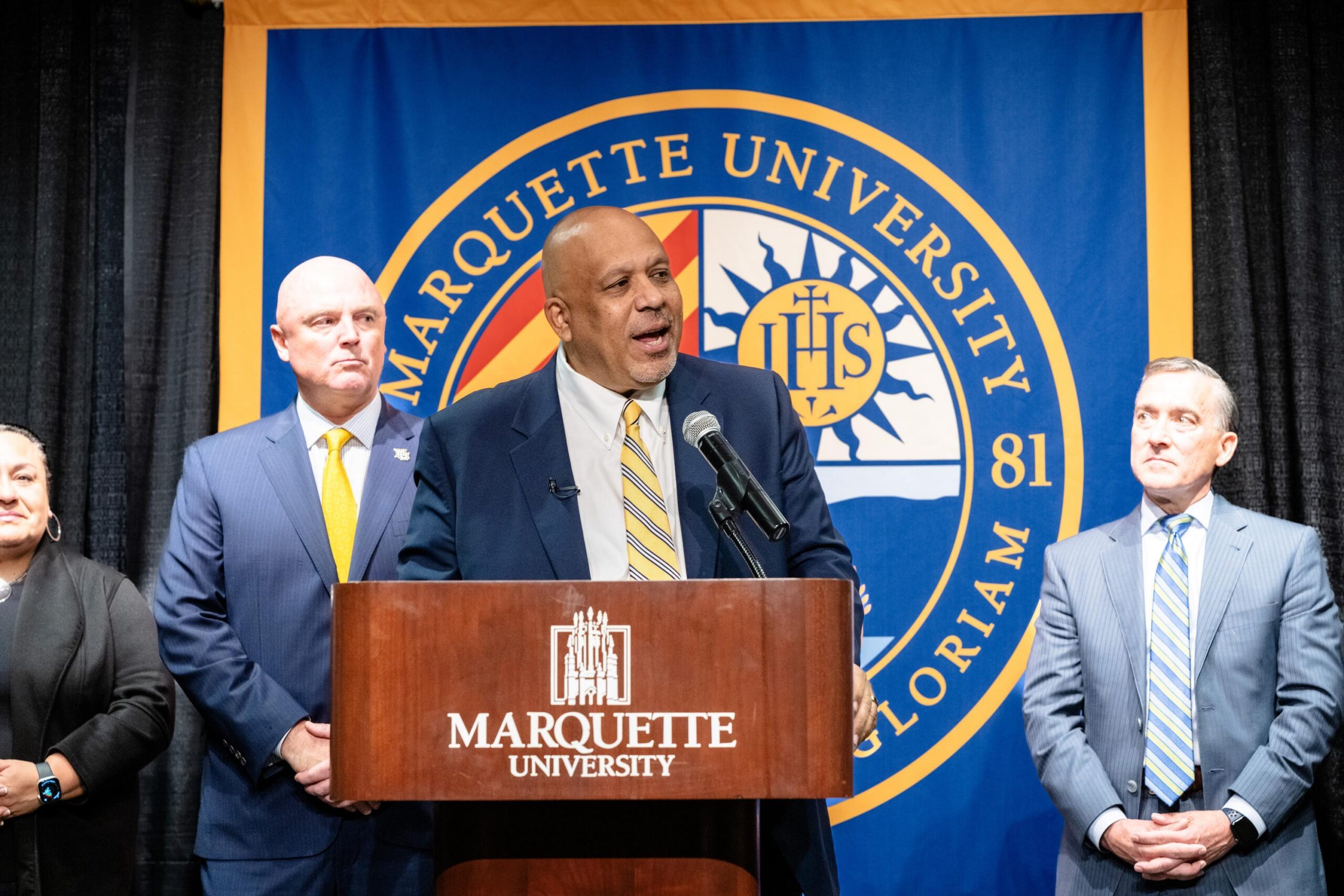 President Ah Yun stands behind the podium while being introduced as Marquette's 25th president.