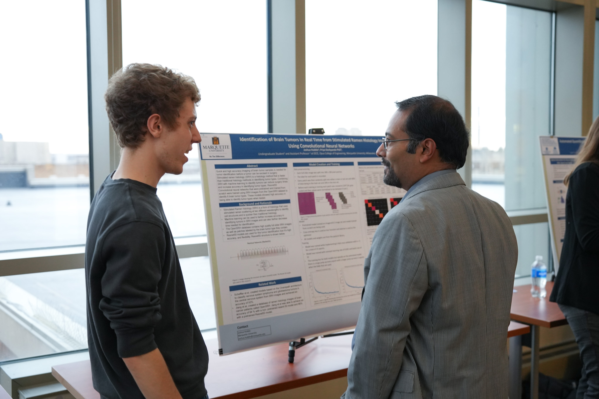 student and faculty talking in front of research poster