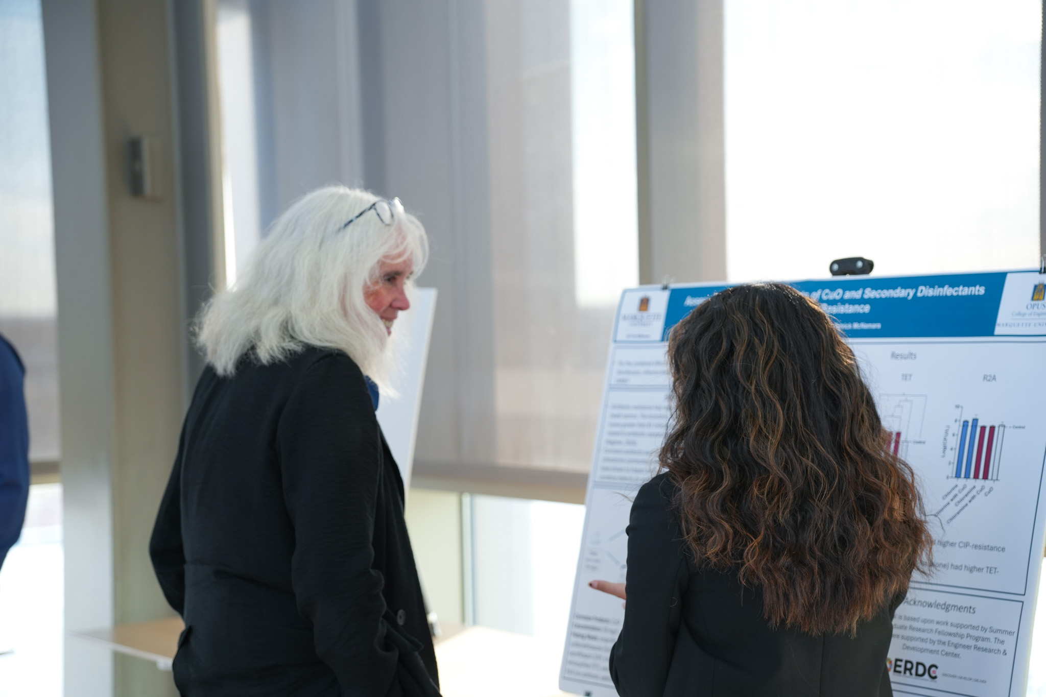 student and faculty talking in front of research poster