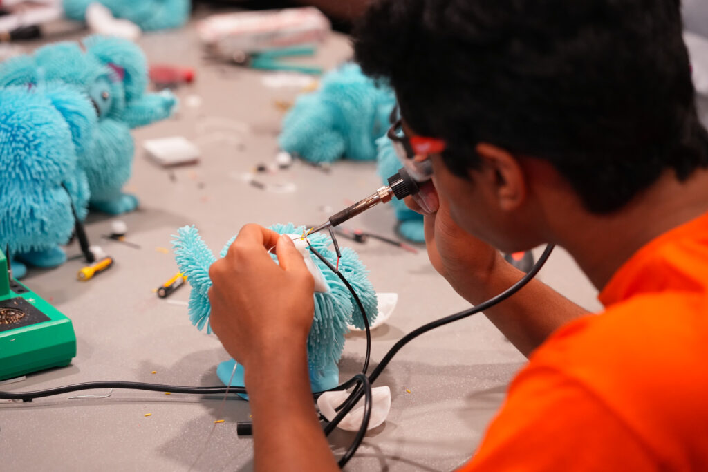 students collaborating with hand tools to adapt toys