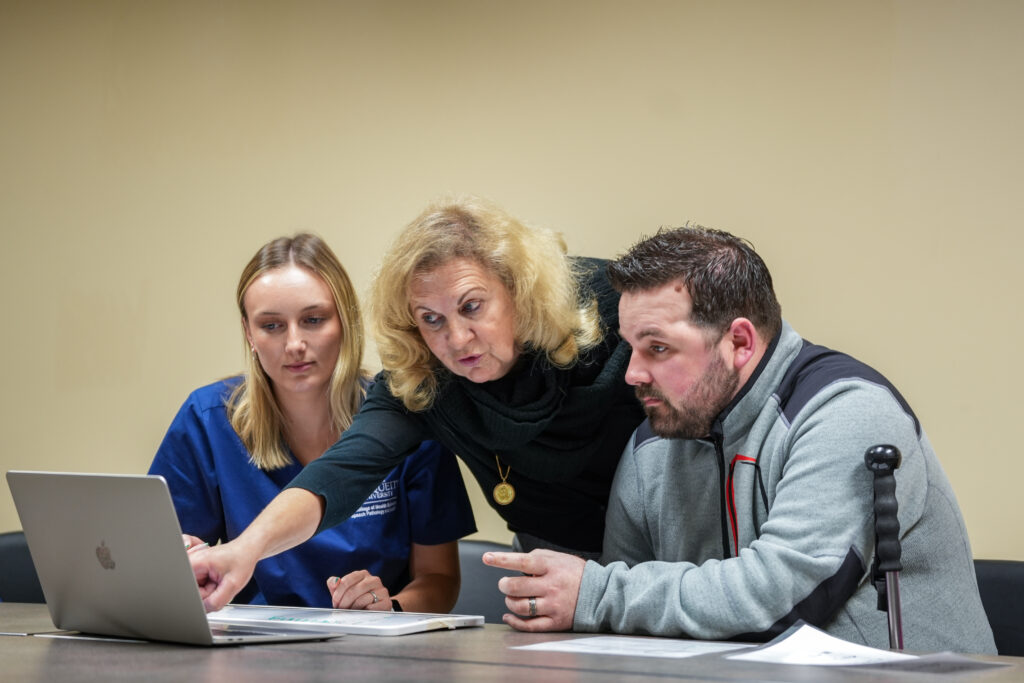 A woman directs a patient on a computer screen. 