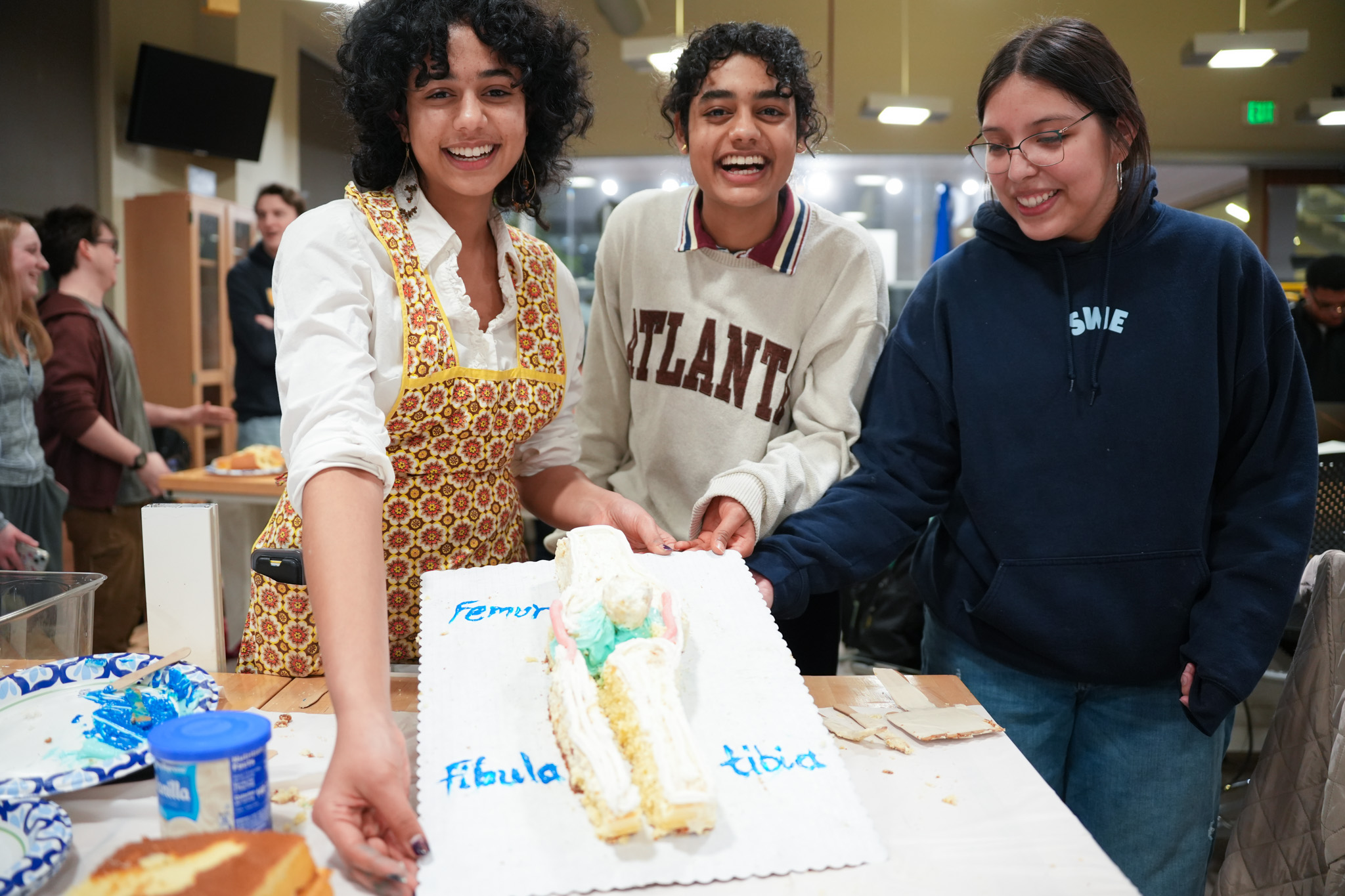 Students posing with biological knee cake at cake decorating contest