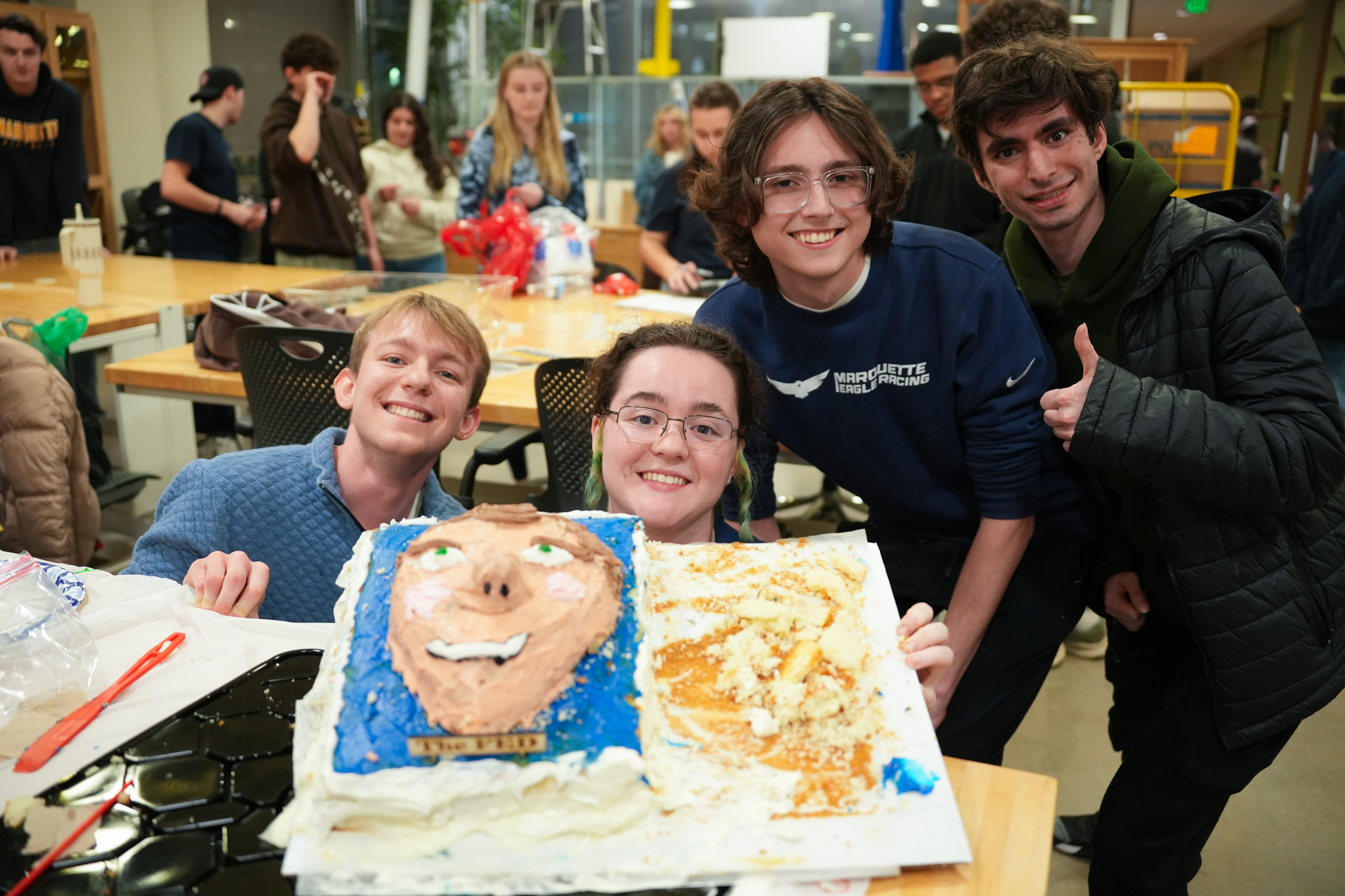 Students posing with faculty cake at cake decorating contest
