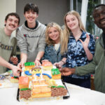 Students posing with lego cake at cake decorating contest