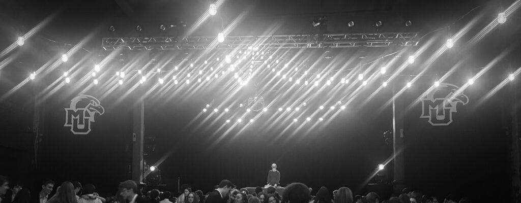 DJ at front of crowded dance hall with Marquette branding