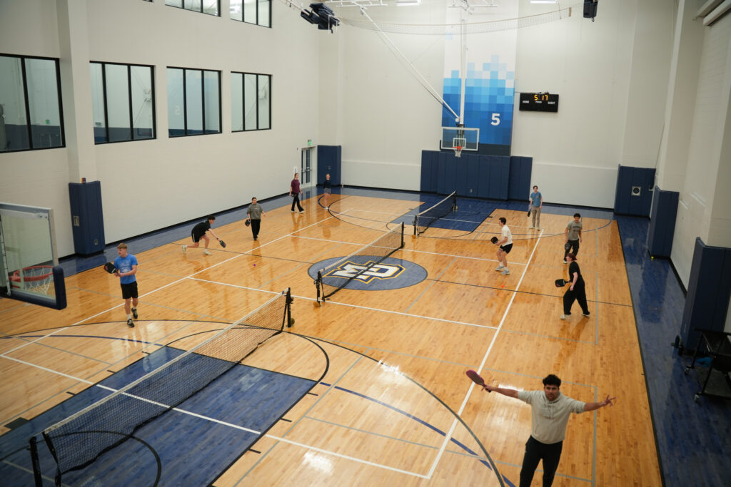 gym with three student pickleball matches 