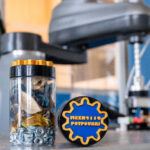 Blue and gold potpourri containers labeled "MEEN4110 Potpourri" in front of a robotic arm lab experiment