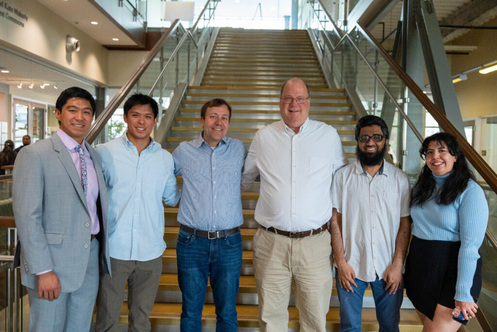 students and faculty posing together in front of staircase at Design Day event